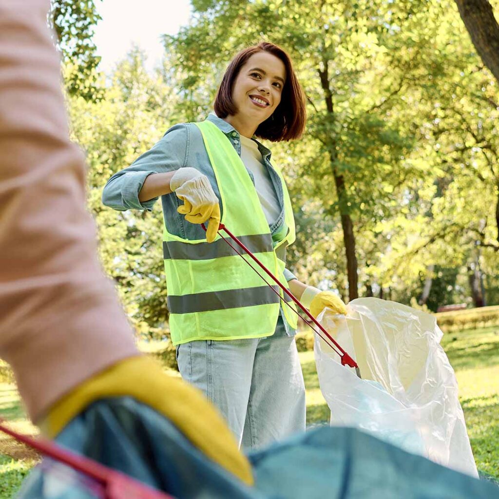 Volunteers in high-visibility vests litter picking in Hurst Park with trees and greenery in the background.